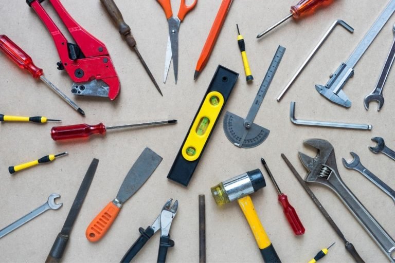 A table featuring a variety of tools, such as hammers and drills, arranged methodically for a workshop setting.